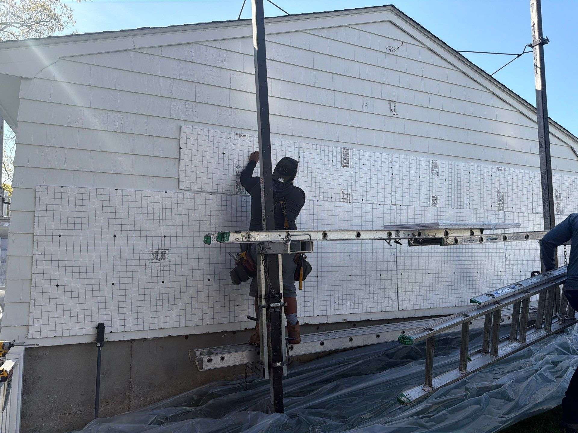 energy efficient roof insulation installation 2026 Professional contractors installing exterior insulation panels for improved home energy efficiency and roofing performance