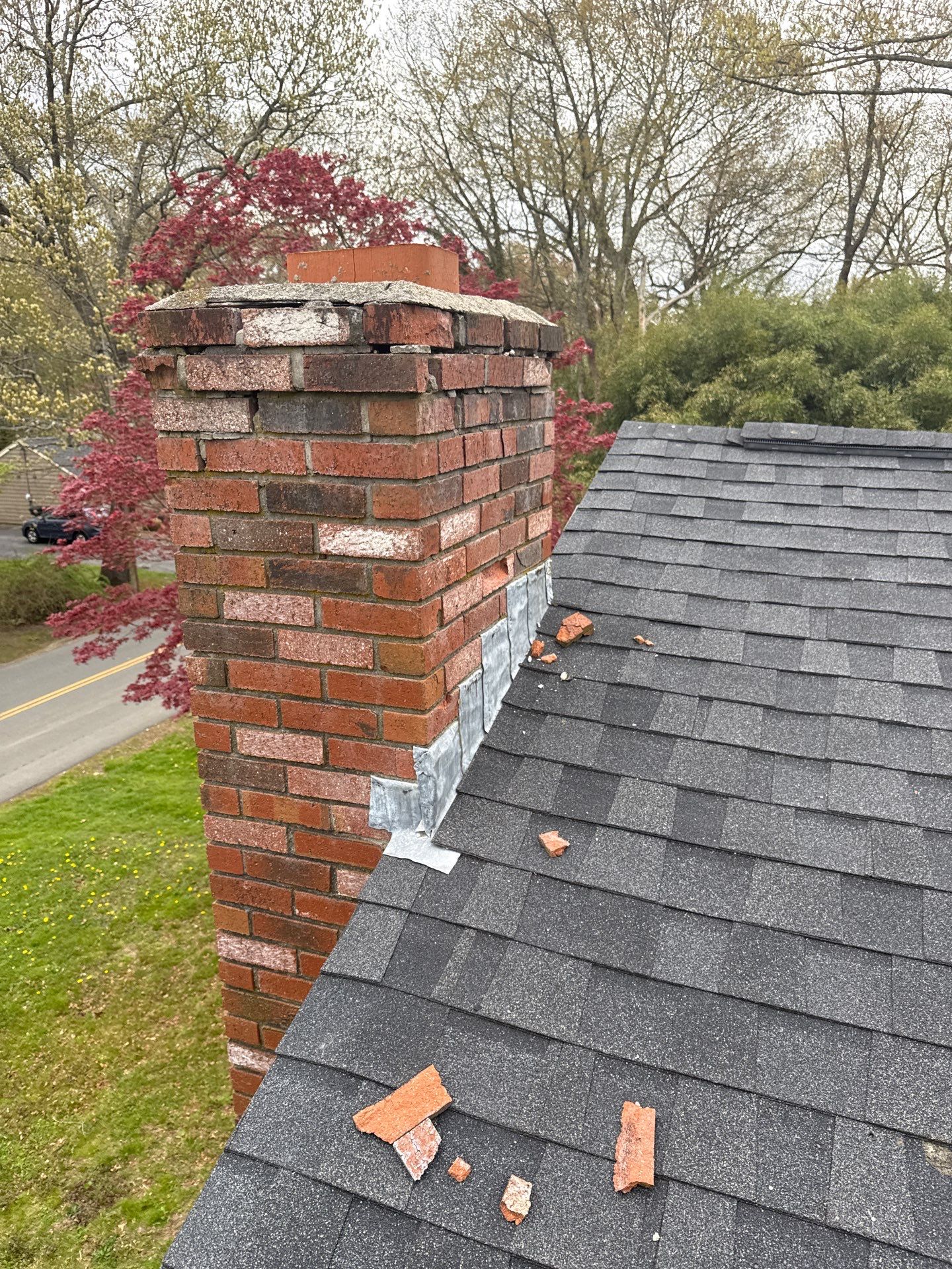 spalling brick chimney roof damage Spalling brick chimney repair needed after deteriorated bricks fell onto an asphalt shingle roof
