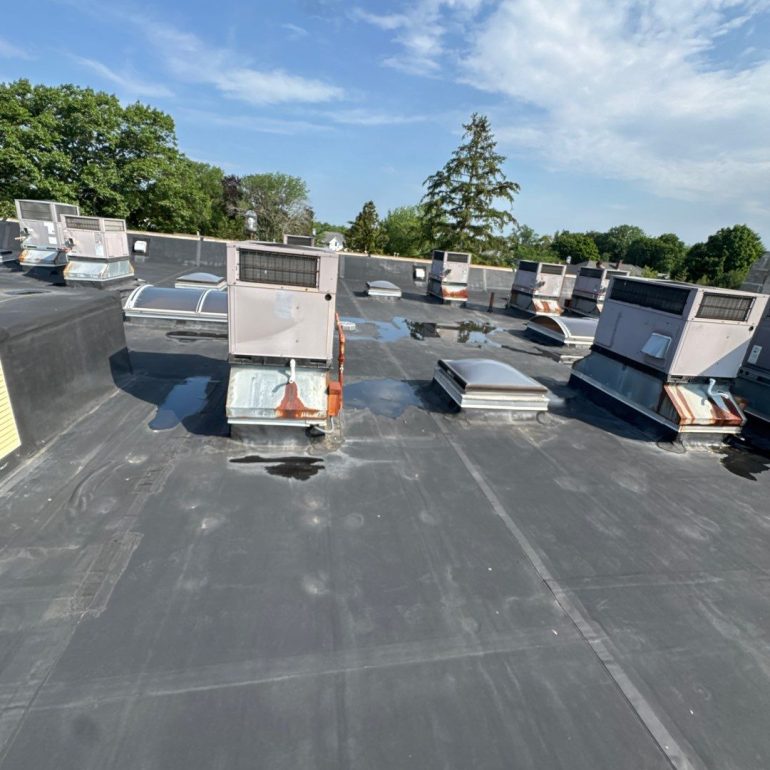 commercial flat roof leak detection Commercial flat roof leak detection inspection showing ponding water around rooftop HVAC units on a membrane roofing system.