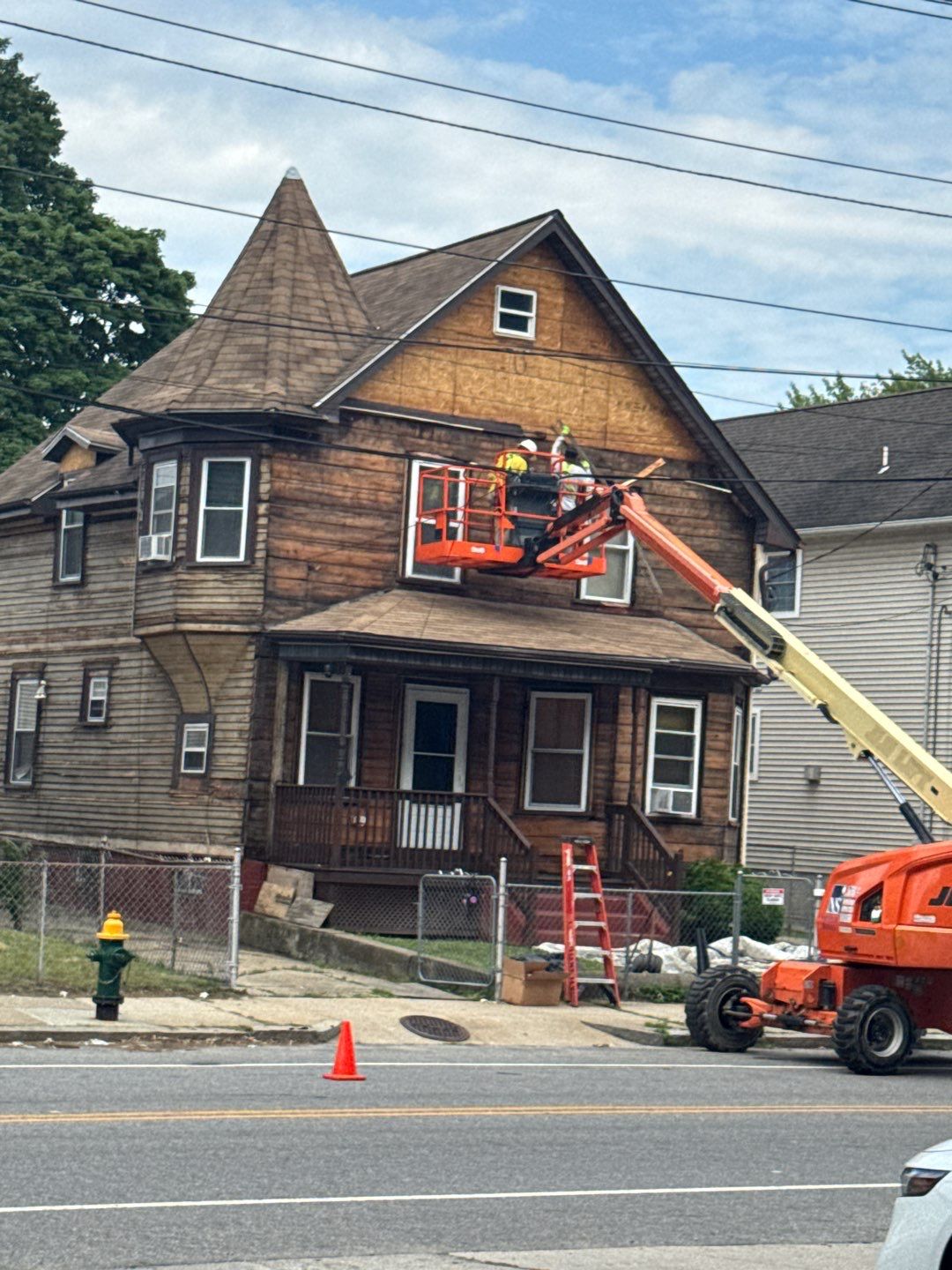 residential wood siding replacement Contractors performing residential wood siding replacement on a two-story home using a boom lift during exterior renovation.